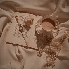 an open book with pearls, beads and a cup of coffee