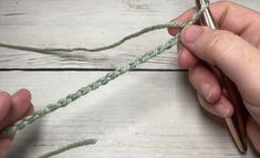 two hands are working on a piece of green yarn