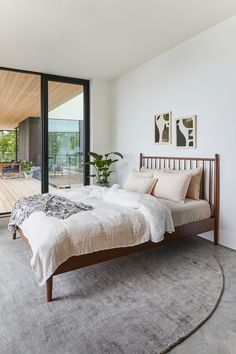 a bed sitting on top of a wooden floor next to a large glass window in a bedroom