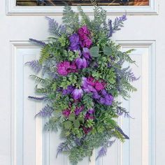 purple flowers and greenery are hanging on the front door