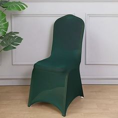 a green plastic chair next to a potted plant on the floor in front of a white wall