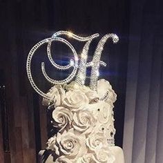 a three tiered wedding cake with white flowers and the letter h on it's side