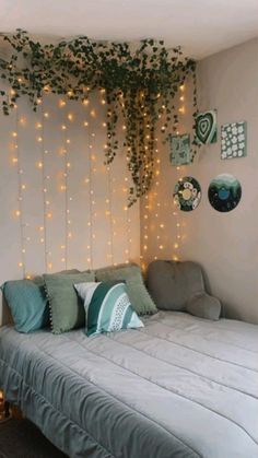 a bed sitting under a tree with lights on the wall next to it's headboard