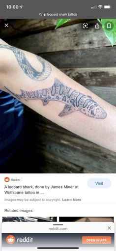 a man with a tattoo on his arm is looking at an image of a shark