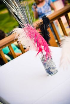 there is a vase with some feathers in it and people sitting at the table behind it