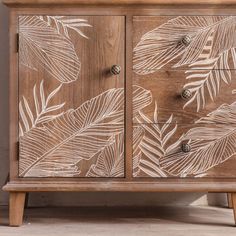 a wooden cabinet with leaves painted on the front and side panels, sitting in a room