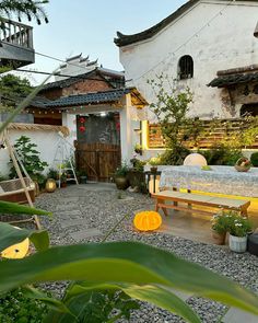 an outdoor area with benches, plants and potted plants on the ground in front of a white building