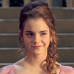 a woman in a pink dress standing next to some stairs and smiling at the camera