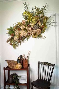 a wooden chair sitting next to a table with flowers hanging from it's side