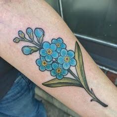 a blue flower tattoo on the arm