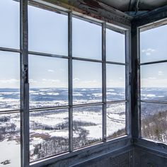 an open window in the side of a building with snow on the ground and trees outside