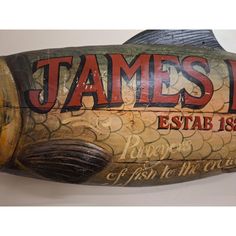 a fish shaped wooden sign with the name james d estab is on it's side