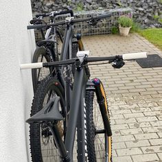 two bikes parked next to each other on a brick walkway near a wall and grass