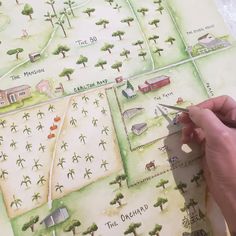 a person is drawing on a map with markers and trees in front of the town