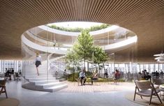 people are sitting at tables in an open area with stairs and trees on the walls