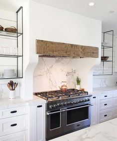 a stove top oven sitting inside of a kitchen next to white cupboards and counter tops