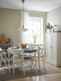 a white table and chairs in a room with a large window behind it on the wall