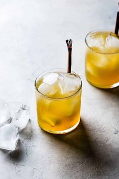 two glasses filled with yellow liquid and ice