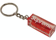 a red box shaped keychain with the word supreme on it's side