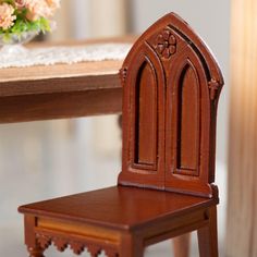 a small wooden chair sitting on top of a table next to a vase with flowers