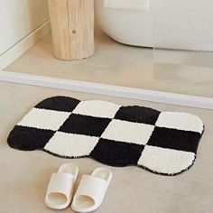 a pair of slippers sitting on top of a rug next to a bath tub