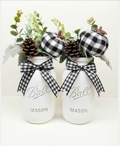 two mason jars decorated with pine cones and plaid bows