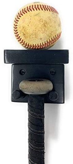 a baseball sitting on top of a black hook with a ball hanging from it's side