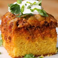 a piece of cornbread casserole topped with sour cream and green garnish