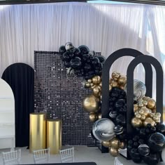 there are many different types of balloons on the table and behind it is a black sign with gold letters