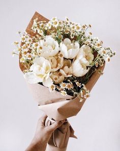 a bouquet of white flowers wrapped in brown paper