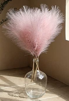 a vase filled with pink feathers on top of a table