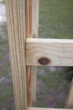 a close up view of a wooden fence with holes in the wood and grass behind it