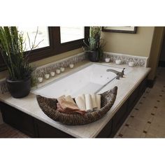 a bathroom with a large jacuzzi tub in the middle and plants on the side