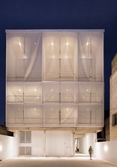 a building with lots of windows on the front and side of it at night time