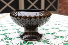 a brown and black vase sitting on top of a table covered in green and white tiles