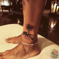 a woman's foot with a palm tree tattoo on the side of her leg