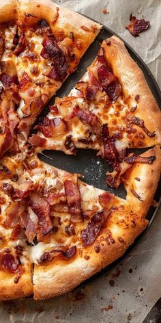 a pizza sitting on top of a pan covered in cheese and bacon slices with one slice missing