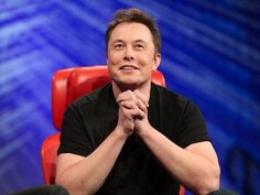 a man sitting in a red chair with his hands clasped