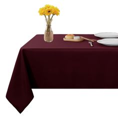 a table topped with a vase filled with yellow flowers next to two plates and a knife