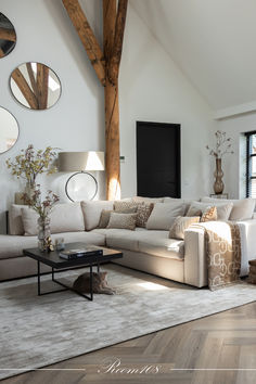 a living room filled with lots of furniture next to a tall wooden beamed ceiling