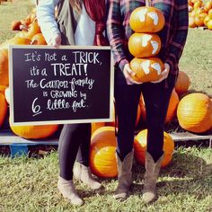 two people standing in front of pumpkins with a sign that says it's not a trick, its a treat