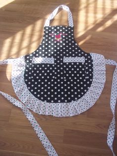 an apron with polka dots on it sitting on top of a wooden floor next to a pair of scissors