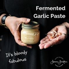 a person holding a jar with garlic paste in it's hands and the text fermented garlic paste