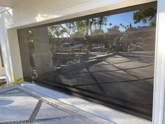 the reflection of cars parked in front of a garage door is seen through an open window