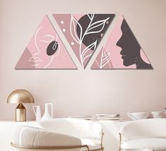 two pink and black paintings on the wall above a white couch in a living room