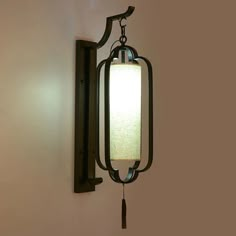 a wall mounted light hanging from the side of a wall next to a lamp shade