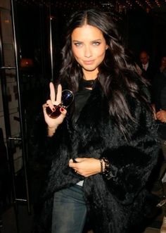 a woman is walking down the street with her peace sign in front of her hand