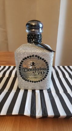 a bottle of perfume sitting on top of a black and white striped table cloth with a bow