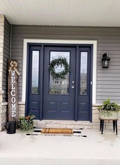 a blue front door with two planters and a welcome sign