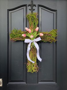 a cross decorated with pink tulips and greenery hangs on the front door